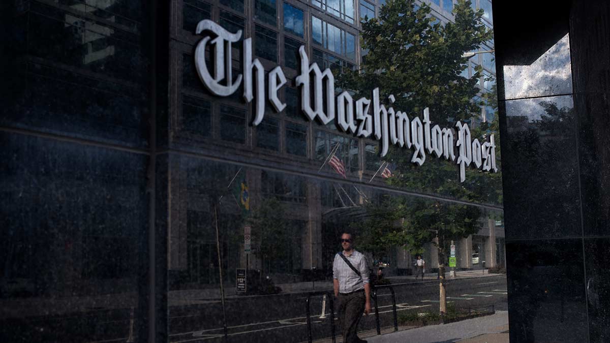 A man walks buy the Washington Post building.